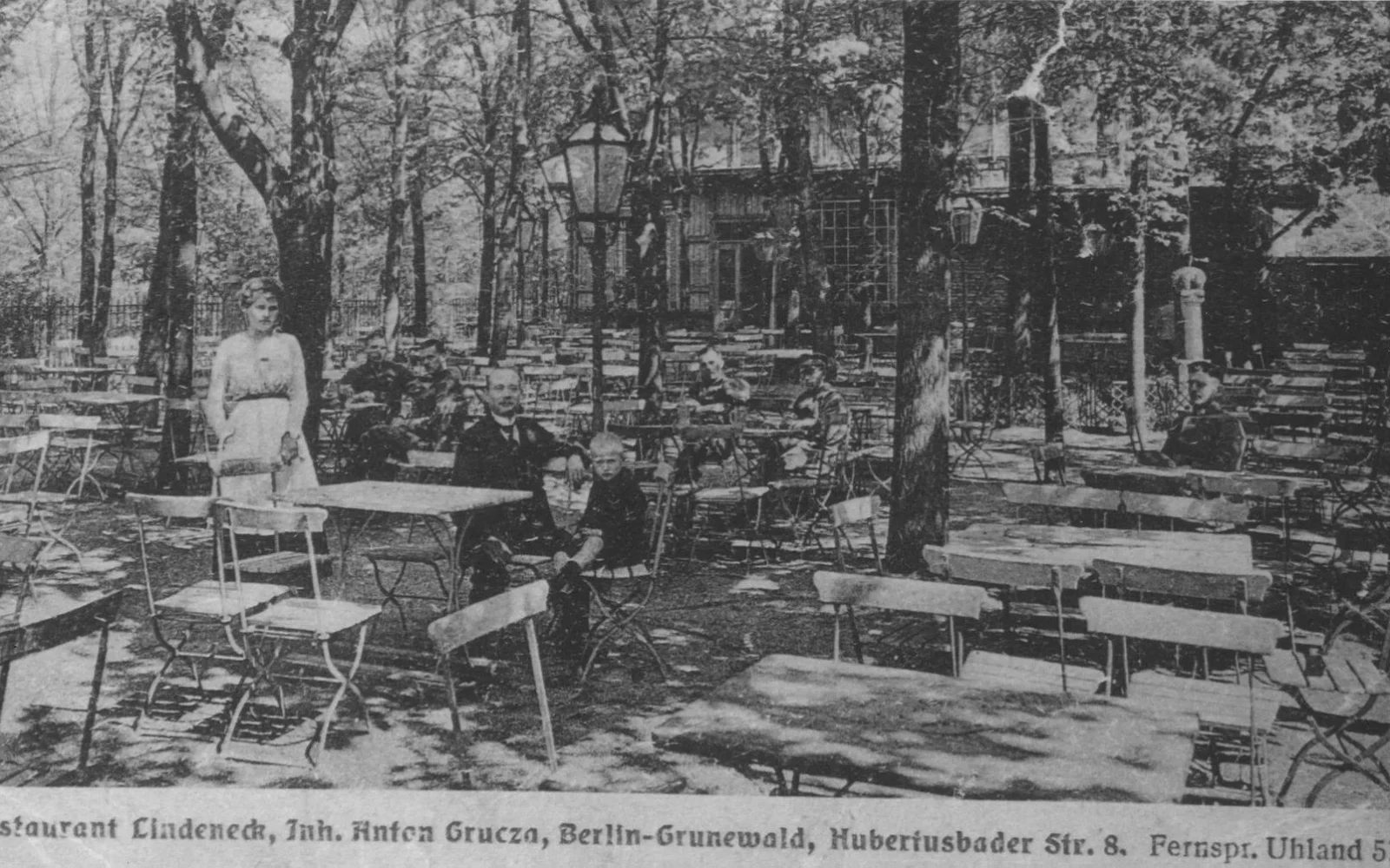 Historische Postkarte aus den 1920er-Jahren: Gäste an Tischen unter hohen Bäumen im Gartenlokal Lindeneck, schwarzweiß